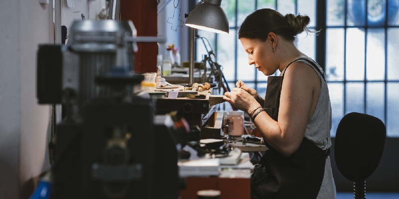 a female jeweler making a piece of jewelry on a workbench