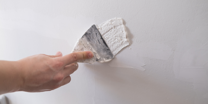 filling in drywall holes with spackle and a knife