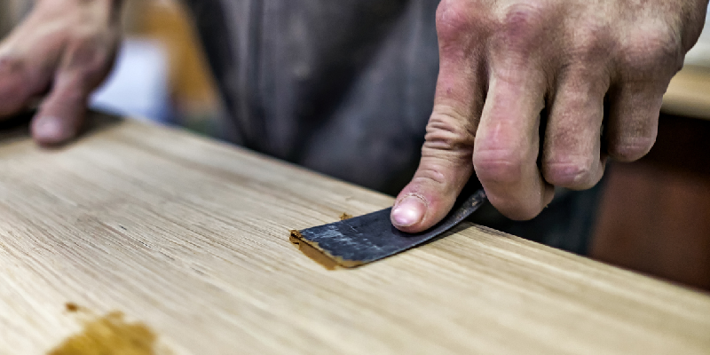 filling in a hole with wood filler and a putty knife