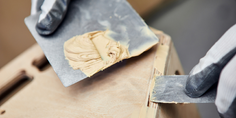 using wood putty to fill in holes on a piece of wooden furniture