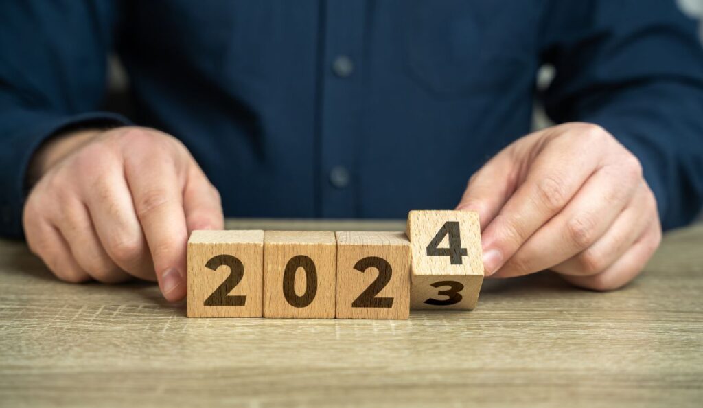 person changing the year from 2023 to 2024 using wooden number blocks